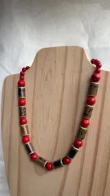 Collar de cuentas con diseño alternado: cuentas redondas de color rojo jaspeado y cuentas cilíndricas de color marrón oscuro con vetas claras.