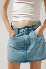 Minifalda de jean celeste con tiro medio, trabillas, cinco bolsillos y cierre frontal con cremallera y botón metálico.