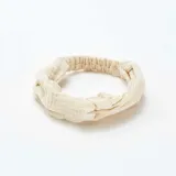 Diadema de tela color beige con diseño trenzado en la parte superior.