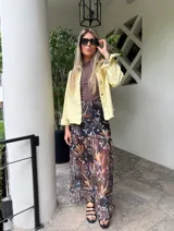 Falda larga de tela estampada con motivos florales en tonos marrones, negros y violetas. Tiene elástico en la cintura y corte acampanado.