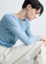 Sweater gris de punto canalé con cuello barco y mangas largas.