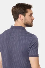 Polo de piqué color azul oscuro con un mini estampado geométrico repetitivo en todo el cuerpo. Presenta cuello y tapeta de botones en color liso, y un pequeño logo bordado en el pecho.