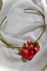 Gargantilla dorada rígida con aplique central de nácar rojo, perlas y piedras color ámbar.