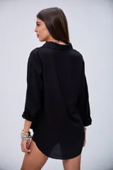 Camisa negra de manga larga con detalles de lentejuelas y bordados en el pecho, cuello camisero y cierre de botones.