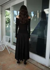 Vestido largo negro con hombros descubiertos, de tejido fluido y diseño evasé.