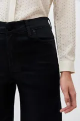 Pantalón de jean negro de tiro alto y pierna palazzo, confeccionado en denim con elastano y coating negro con apariencia similar al cuero.