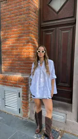 Camisa blanca de broderie con escote en V, abotonada y manga 3/4. Corte oversize, más larga atrás que adelante.