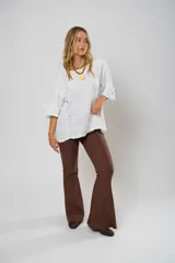 Blusa blanca de lino con corte asimétrico, mangas 3/4 con botones y cuello redondo amplio.