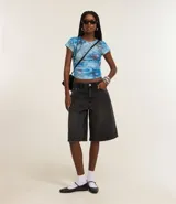 Bermuda femenina confeccionada en jeans color gris oscuro, modelo jorts, con trabillas en la cintura y bolsillos.