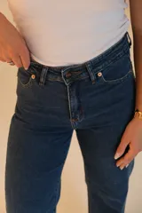Jean wide leg de tiro alto, color azul oscuro. Tiene dos bolsillos redondeados en la cadera en la parte delantera y dos bolsillos en la parte trasera. Cuenta con botón metálico, cremallera y terminación de ruedo desflecado.