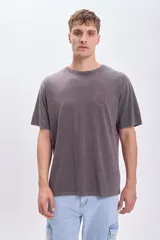 Remera de manga corta gris oscuro con estampa circular en la espalda con un sol en el centro y la frase "Catch the sun, chose the surf".