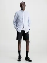 Camisa celeste de lino y algodón, de corte regular, manga larga, cuello en punta, cierre de botones oculto y bolsillo de parche en el pecho con monograma de Calvin Klein en la misma gama de tonos.