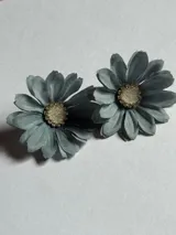Par de caravanas con forma de flor de tela color celeste, con centro de resina y strass. Cierre a presión.