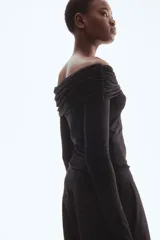 Top negro ajustado de punto elástico con hombros descubiertos, mangas largas, escote ancho con doblez y laterales fruncidos.