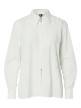 Camisa blanca de corte holgado, con cuello clásico, mangas largas con puños abotonados y cierre frontal con cremallera.