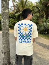 Remera beige de algodón con estampa en la espalda de una flor sonriente sobre un fondo a cuadros azules y texto "FLOWKERS".