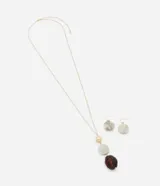 Conjunto de collar largo con cadena dorada y colgantes de resina en tonos marrón, blanco y dorado, acompañado por caravanas anzuelo con colgante de resina.