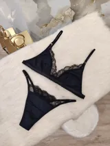 Conjunto de lencería negro, compuesto por un corpiño triangular de algodón con detalles de encaje y una tanga de algodón con detalles de encaje.