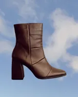 Botín de cuero color marrón con caña media, punta fina y taco geométrico de 10 cm.