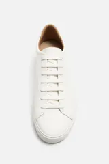 Zapatillas blancas de cuero sintético con cordones, forro interior y plantilla color beige.