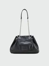 Bolso negro de cuero con textura granulada, con el nombre de la marca grabado en relieve en el frente. Tiene doble asa corta superior y una correa larga de cadena plateada con aplique de cuero en el hombro.