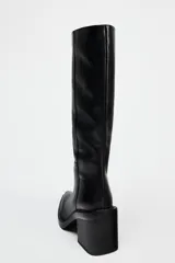 Bota de cuero negra con caña alta, punta cuadrada y tacón ancho.