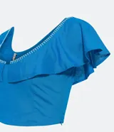 Blusa cropped de lino color azul, sin mangas, con volado en los hombros y busto, escote en U y pespuntes contrastantes.
