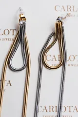 Aros colgantes con diseño irregular y acabado martillado, combinando dorado y plateado. Fabricados en acero quirúrgico hipoalergénico con baño metálico bicolor.