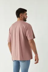 Remera color rosa viejo de corte amplio con estampa en el frente que incluye texto y diseño gráfico.