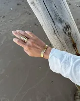 Pulsera tipo esclava abierta, con acabado rústico y textura irregular, en tono plateado. Se vende por unidad.