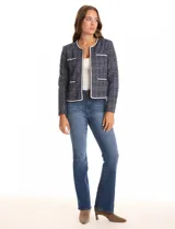 Chaqueta de tweed azul con sutiles destellos de lúrex, cuello a la base y abertura frontal. Tiene bolsillos delanteros decorativos y manga larga con tres botones metálicos dorados en cada puño. Las terminaciones del cuello, apertura frontal, bolsillos y ruedo tienen vivos a contratono. Forro interno a tono.