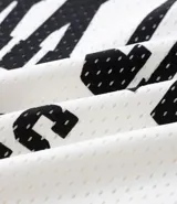 Remera de hombre con corte boxy, confeccionada en tejido mesh (malla) blanco, con cuello en V y estampa arqueada en negro que dice "NEW YORK CITY ATHLETICS".