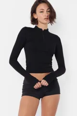 Top manga larga gris de punto roma, con media polera y cuello con cierre de nylon a tono. Mangas con mitones en los puños y estampa de isologo con serigrafía al tono en el delantero.