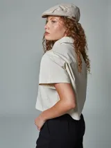 Camisa corta de manga corta, color crudo, con cuello camisero y un bolsillo frontal.