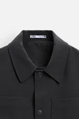 Sobrecamisa verde oscuro de corte cuadrado, con cuello solapa, manga larga con puños abotonados, bolsillos de parche en el pecho y bolsillos laterales en la cadera. Cierre frontal con botones.