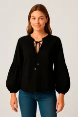 Blusa negra con escote en V con lazos, mangas largas abullonadas y puños elásticos.
