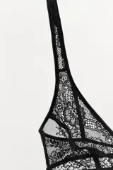 Bralette triangular de encaje negro, con escote pico y tirantes anchos ajustables. Cierre en espalda con ganchos metálicos.