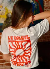 Remera blanca de algodón con estampa roja en la espalda que incluye el texto "LE SOLEIL" y un sol estilizado.