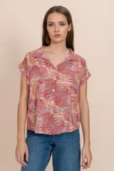 Camisa de manga corta color coral con estampado de hojas de palmera en tonos blanco y amarillo.