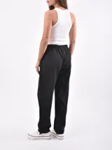 Pantalón de vestir color negro, de corte recto, con bolsillos laterales y traseros. Se ajusta a la cintura con cinturón de cuero marrón.