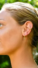 Aros dorados tipo argolla con incrustaciones de circonitas verdes y dije colgante de circonita verde en forma de lágrima.