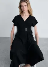 Vestido midi negro con escote en V, mangas cortas tipo kimono, falda acampanada con corte asimétrico y cinturón con hebilla metálica.