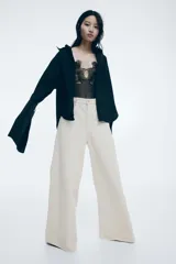 Pantalón de jean color crema, de corte amplio y cintura alta, con detalle de trenzado en la pretina.