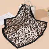 Pañuelo cuadrado de tela fina con estampado animal print en tonos beige y negro, con borde liso negro.