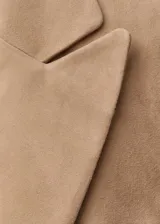 Blazer color beige de gamuza, con cuello de solapa, cierre de un botón, dos bolsillos frontales con solapa, mangas largas con puños abotonados y forro interior.