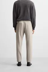 Pantalón color arena de corte recto, confeccionado en tejido elástico. Cuenta con cintura elástica ajustable con cordón, bolsillos laterales y bolsillos de vivo en la parte trasera.