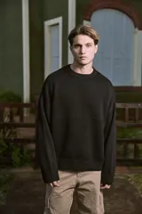 Sweater negro de tejido plano con fit oversize y hombros caídos. Cuello redondo y mangas largas.
