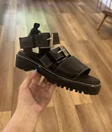 Sandalias negras de cuero con plataforma track y hebillas plateadas.