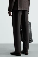 Pantalón de vestir negro de corte recto, confeccionado en tejido de algodón con acabado ligeramente encerado. Cuenta con bolsillos laterales y traseros de vivo. El cierre frontal es con cremallera y gancho metálico oculto.