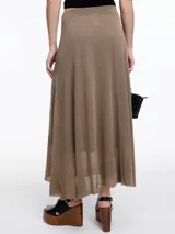 Falda larga evasé de punto con lurex, color negro. Confeccionada en tejido liviano con sutil brillo, tiene un corte evasé que acompaña el movimiento del cuerpo. Su diseño minimalista y su silueta fluida la convierten en una prenda versátil. Cintura plana y terminación ligeramente transparente en el ruedo.